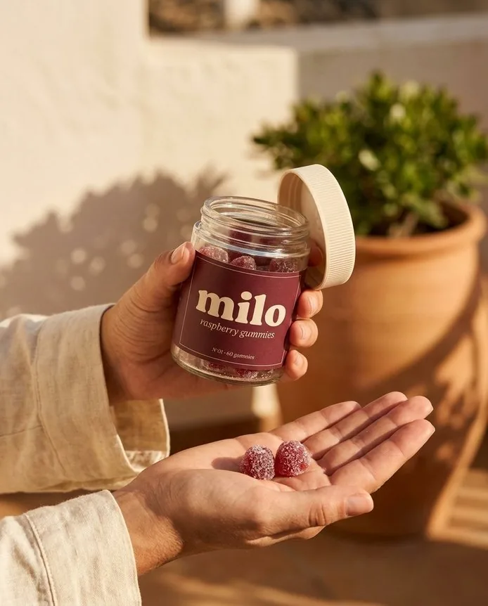 A hand holding the milo jar on a sunny terrace